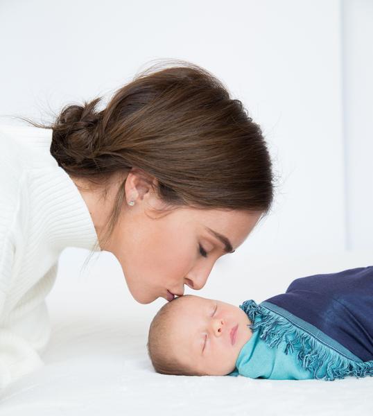 Mom kissing baby in swaddle blanket