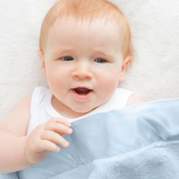 Little Giraffe baby and toddler blankets shown in a nursery setting
