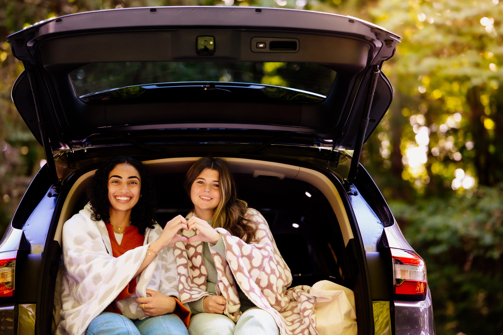 two women in a truck of a car with blankets