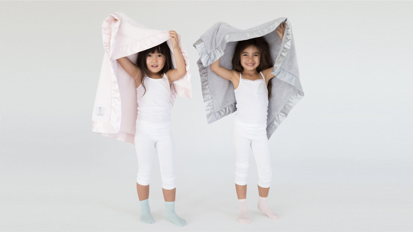 Girls holding Little Giraffe Chenille Baby Blankets