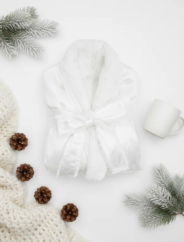 White robe surrounded by pine cones and branches on a light background
